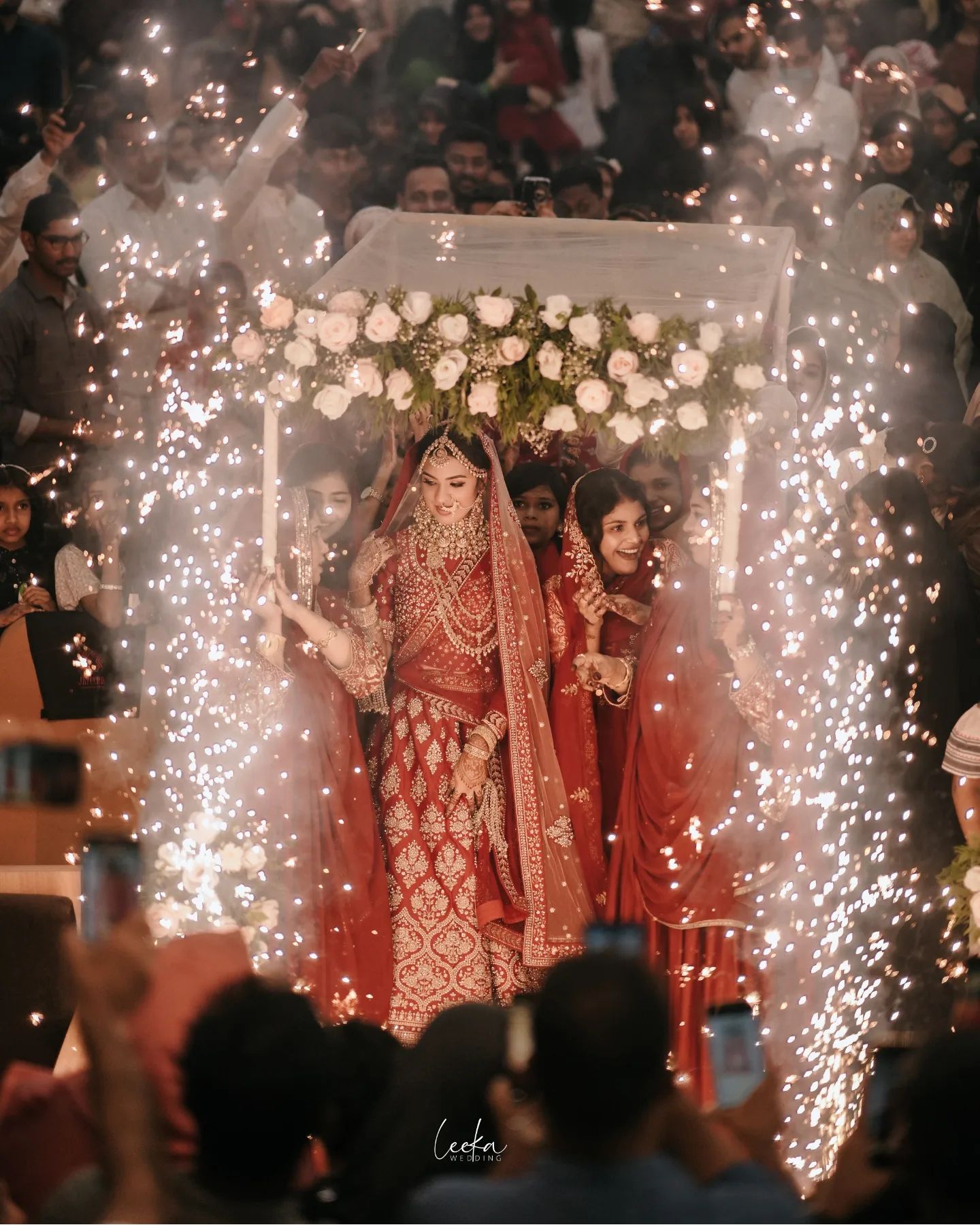 A wedding photographer in Bangalore taking a photo of a bride under a floral arch